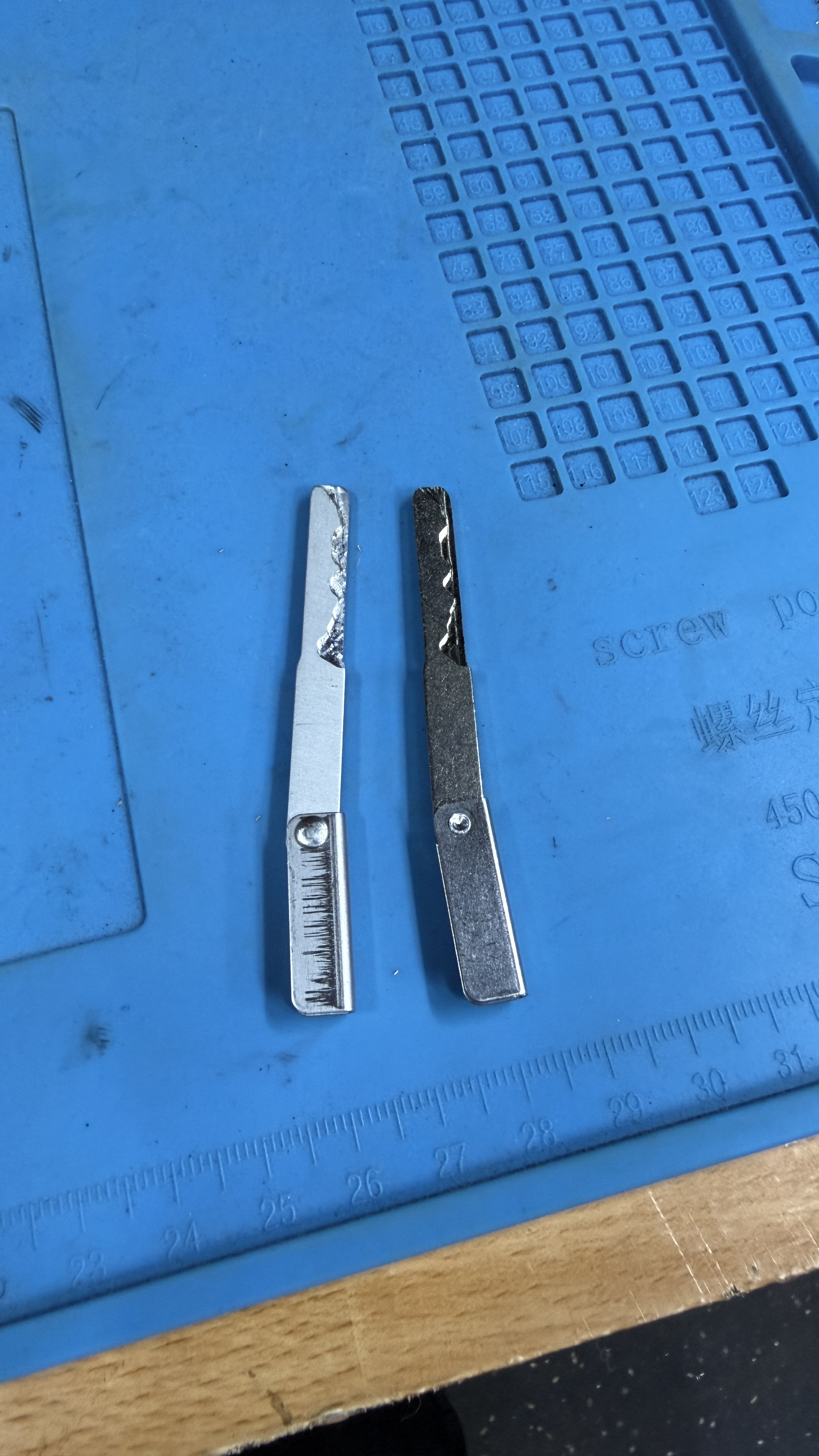 Two finished 2013 Land Rover Range Rover emergency key blades on a blue anti-static work mat after being cut by KeyLogik