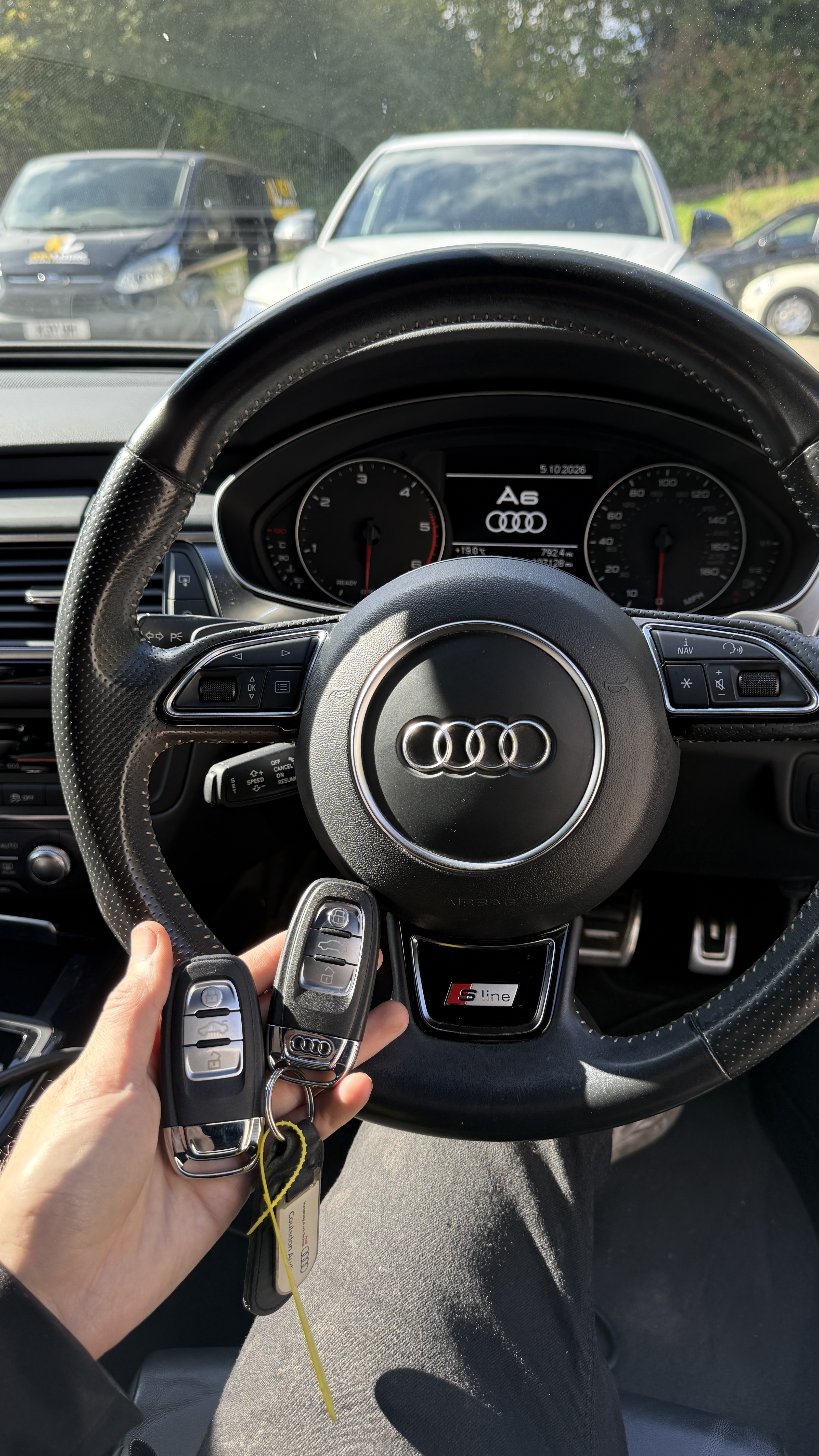 Two Audi keys held at the steering wheel of an Audi A6 S Line after programming by KeyLogik