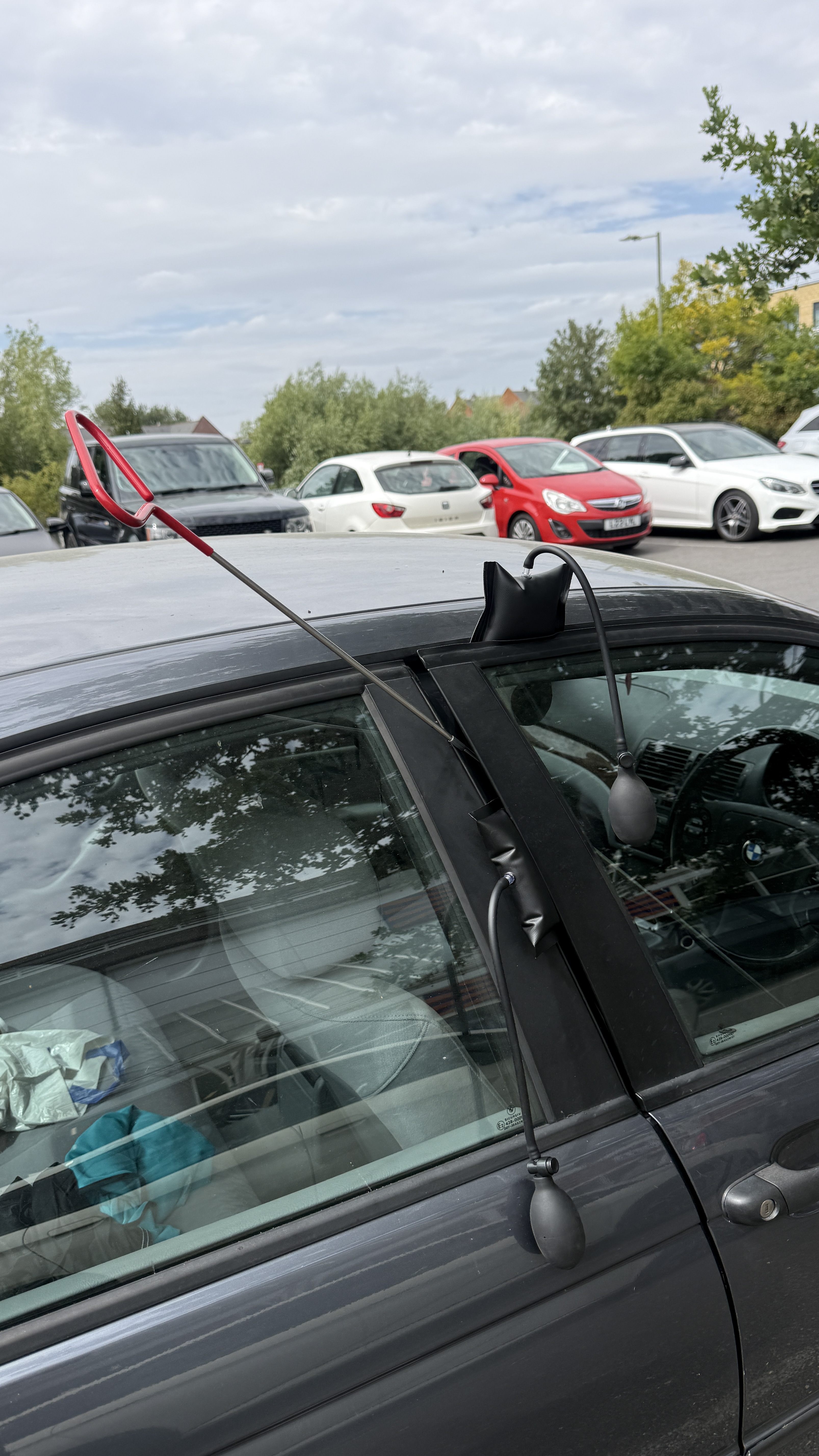 KeyLogik carrying out non-destructive vehicle entry on a locked car using professional air wedges and a reach tool