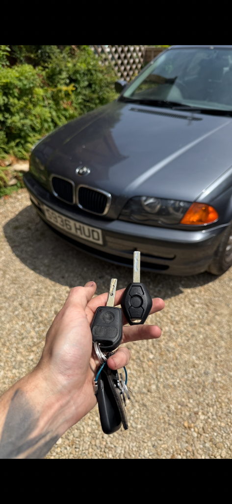 New replacement remote key held alongside the original key in front of a vehicle