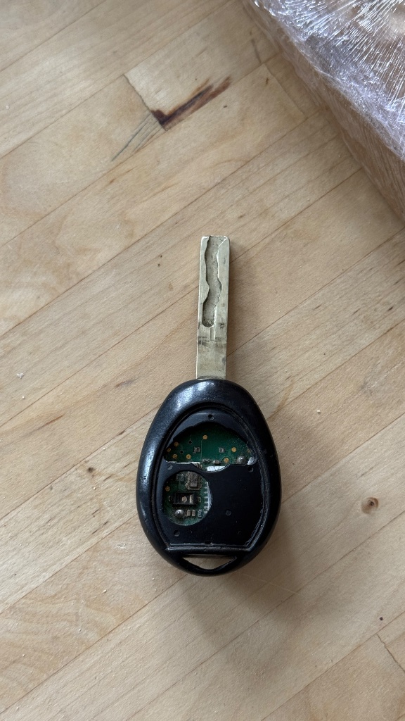 Faulty car key remote with worn-away rubber button pad exposing the green circuit board and broken micro switches