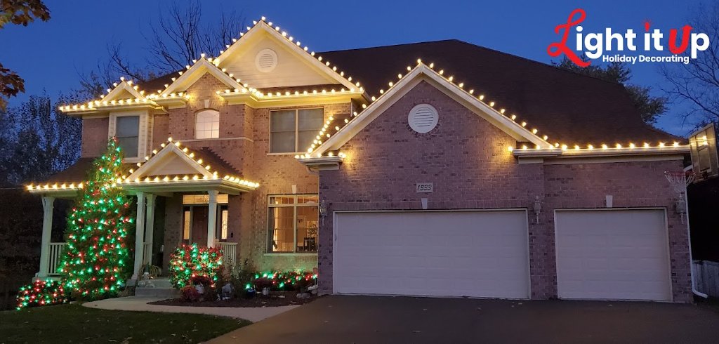 Warm white roofline and red green lit Christmas tree on brick home