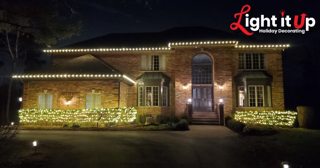 Warm white roofline and bush Christmas lights on large brick home