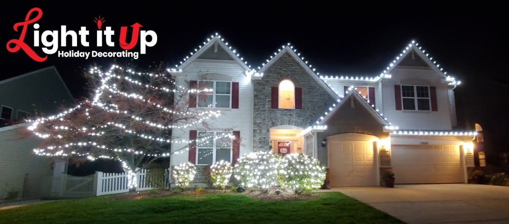 Pure white roofline and outer wrapped tree and bush lights on stone home