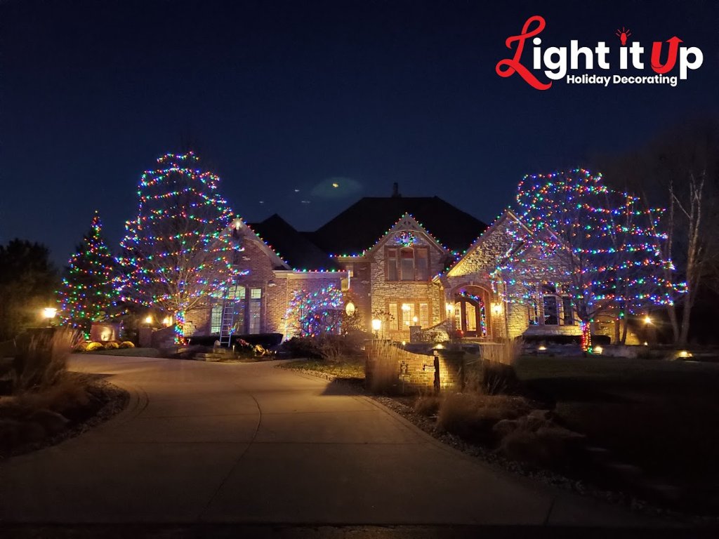 Multicolor outer wrapped trees and roofline lights on large stone home