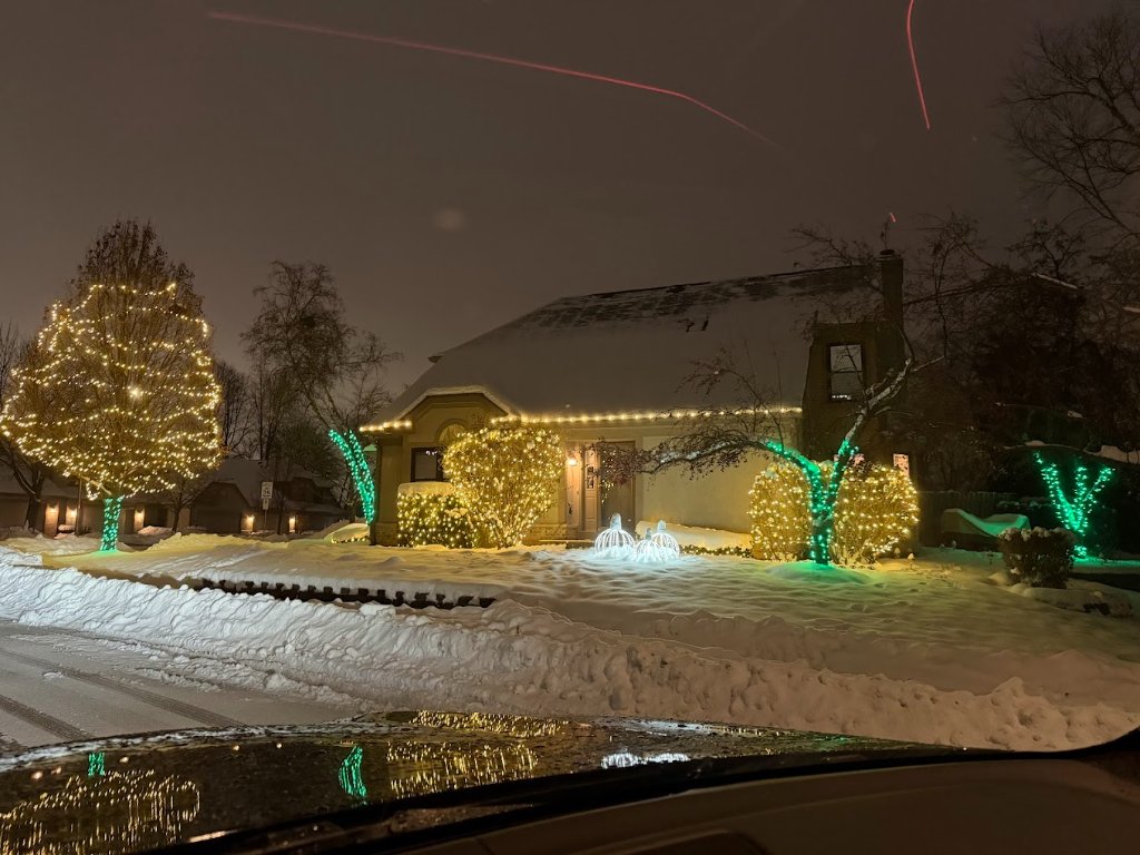 Full home custom Christmas display with warm white and teal tree lights in snow