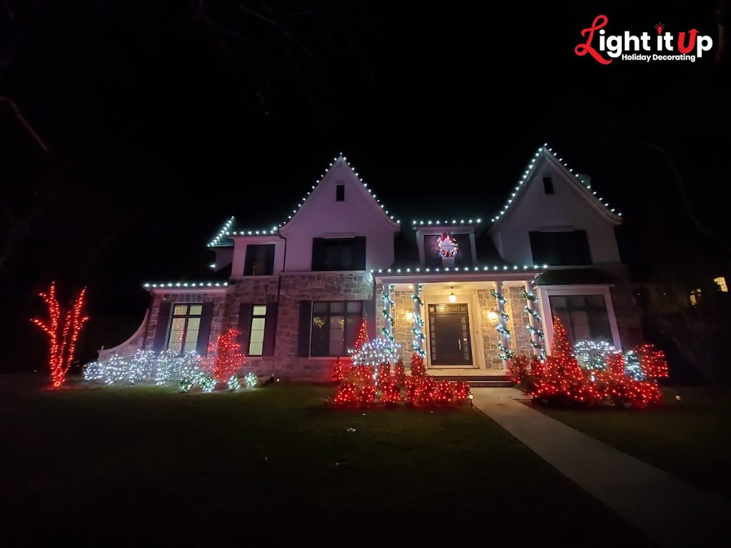White roofline lights with red and white bush lighting and garland columns