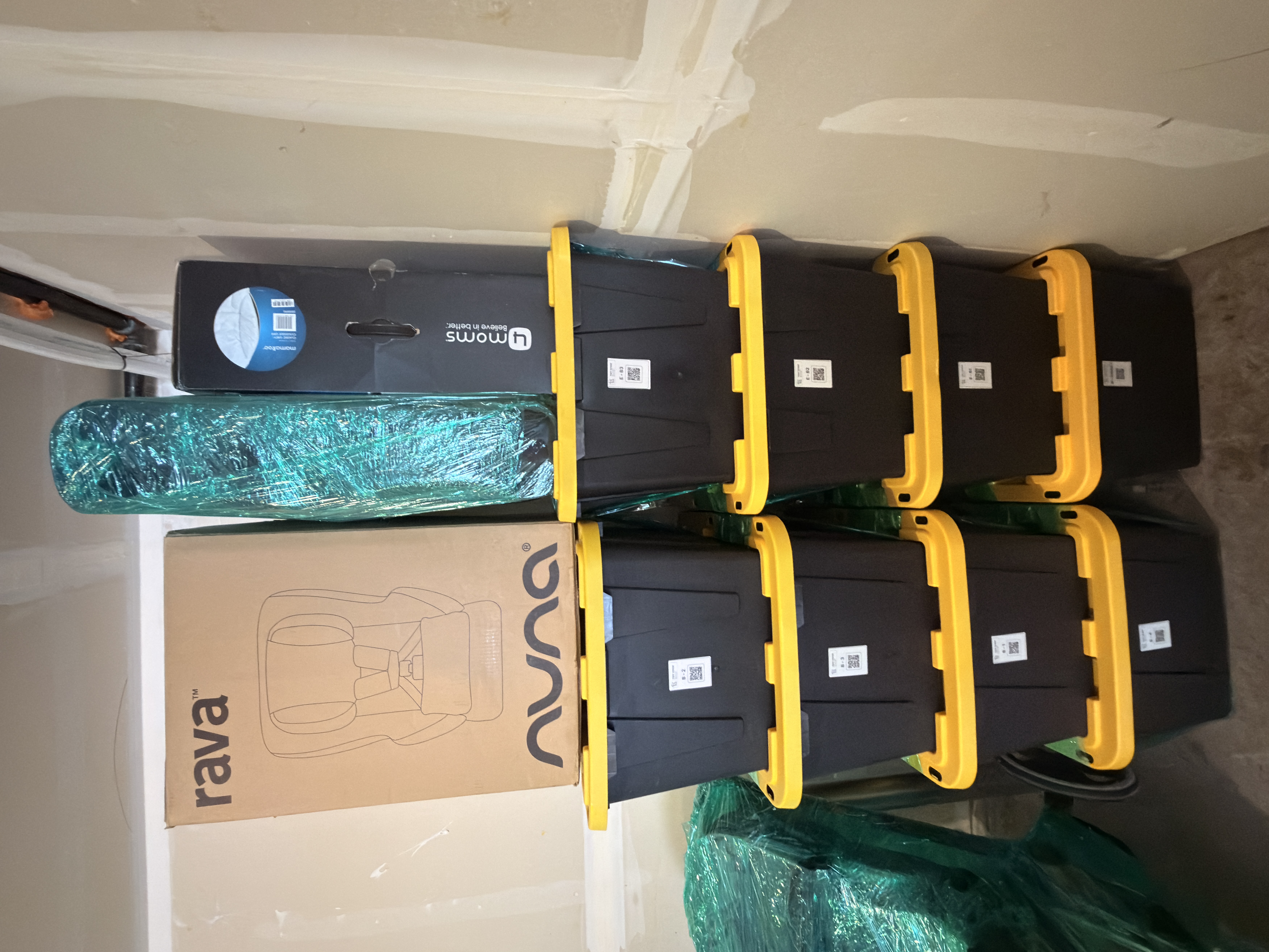 A 2x4 grid of black storage totes with bright yellow lids, each labeled with a small white QR code sticker on the front.