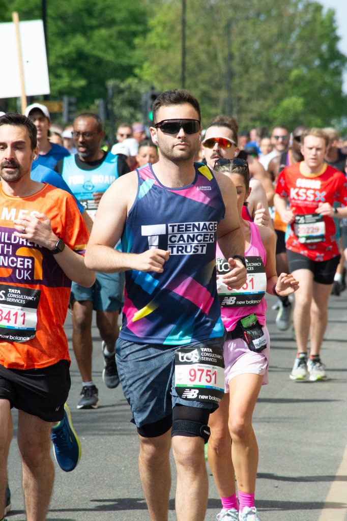 Runners past a large crowd on a wide road