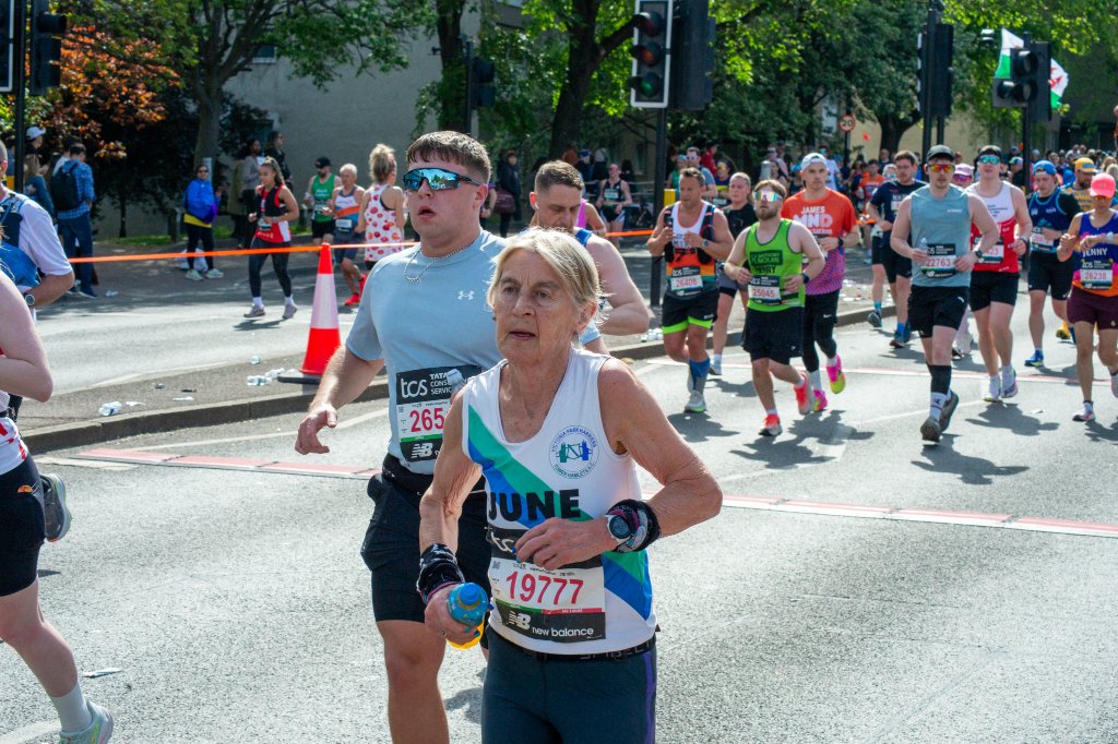 Woman offering a can of Coke to runners
