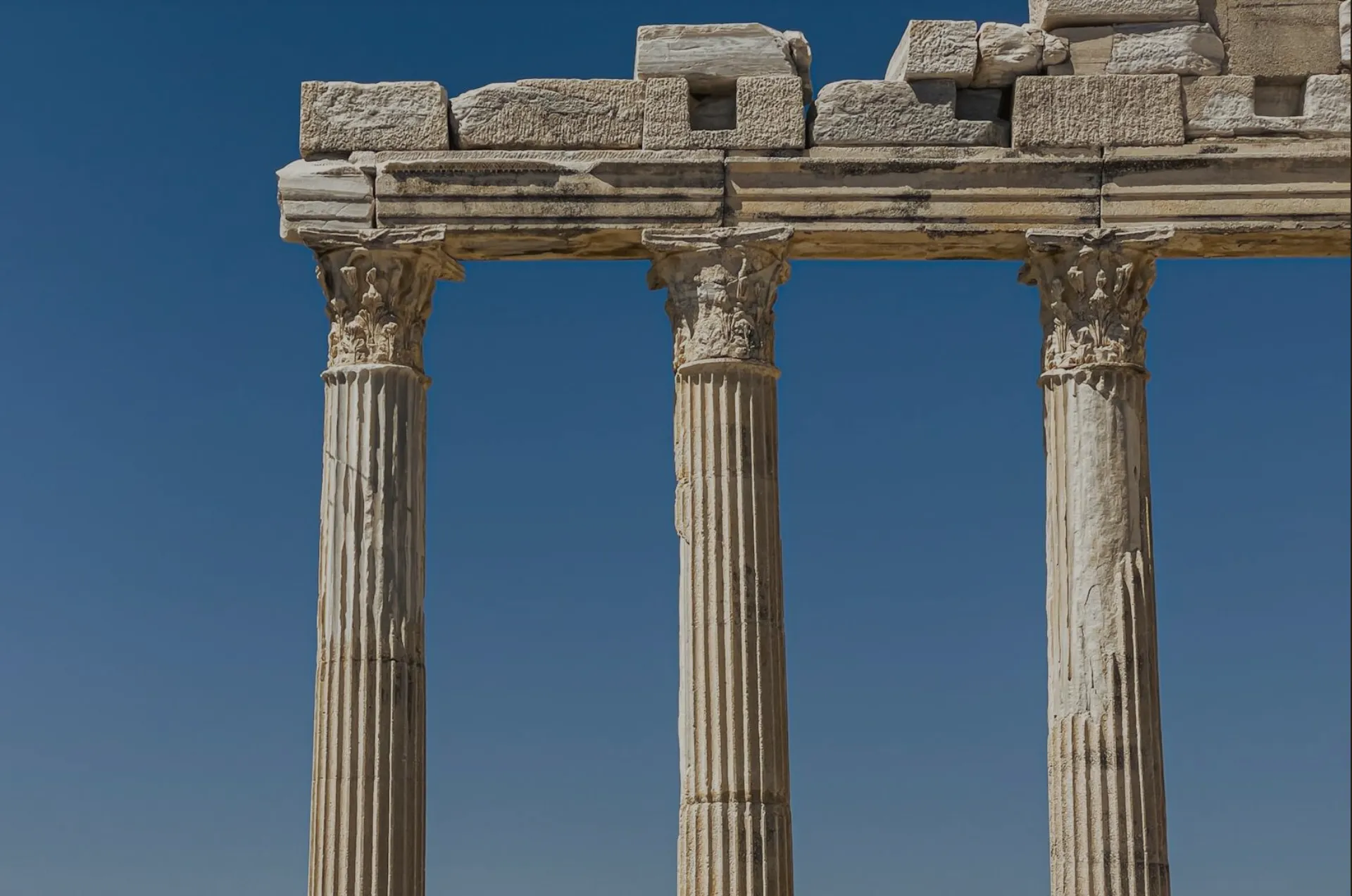Ancient stone columns under a deep blue sky