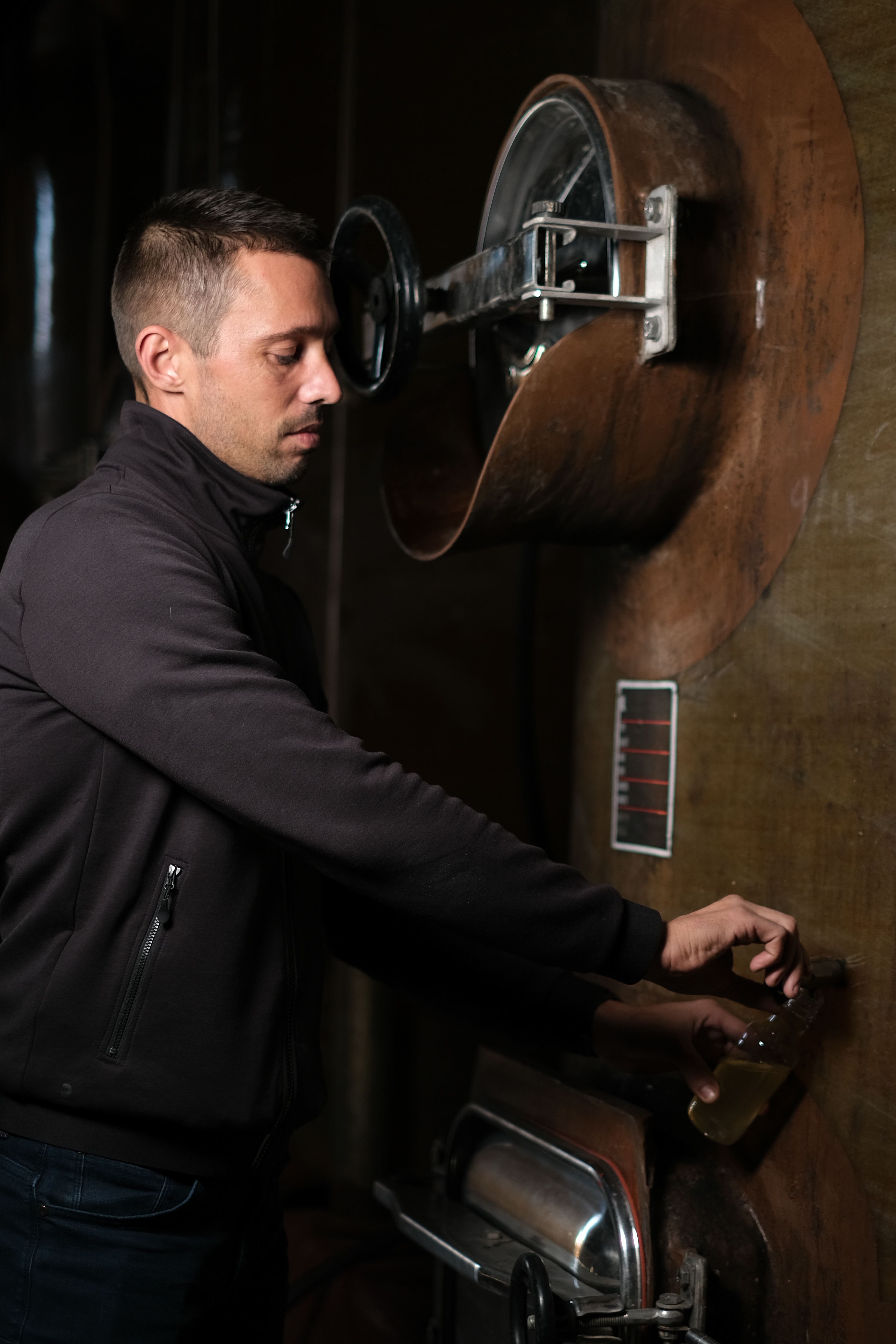 Camille, maître de chai, prélevant du vin au robinet d’un foudre