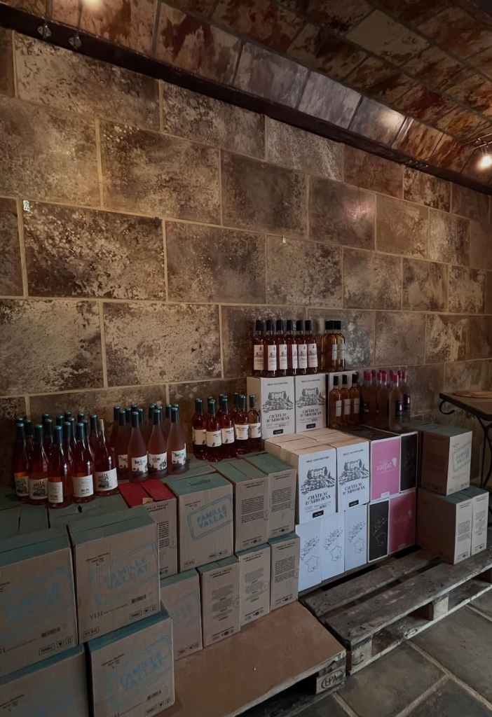 Bouteilles et cartons de la Famille Vallat au mur de pierre de la cave