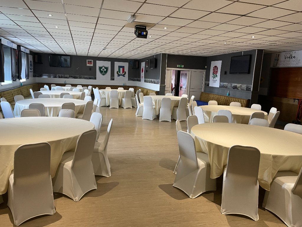 Function hall with round tables and gold chair covers