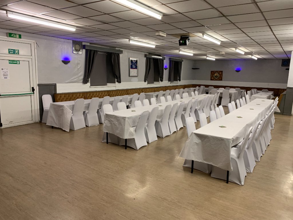 Function hall setup with round tables and white chair covers