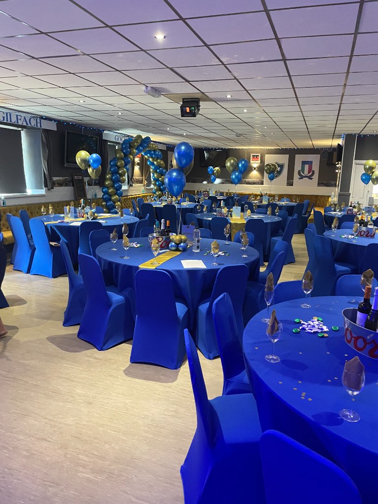 Decorated function hall with blue chair covers and balloons