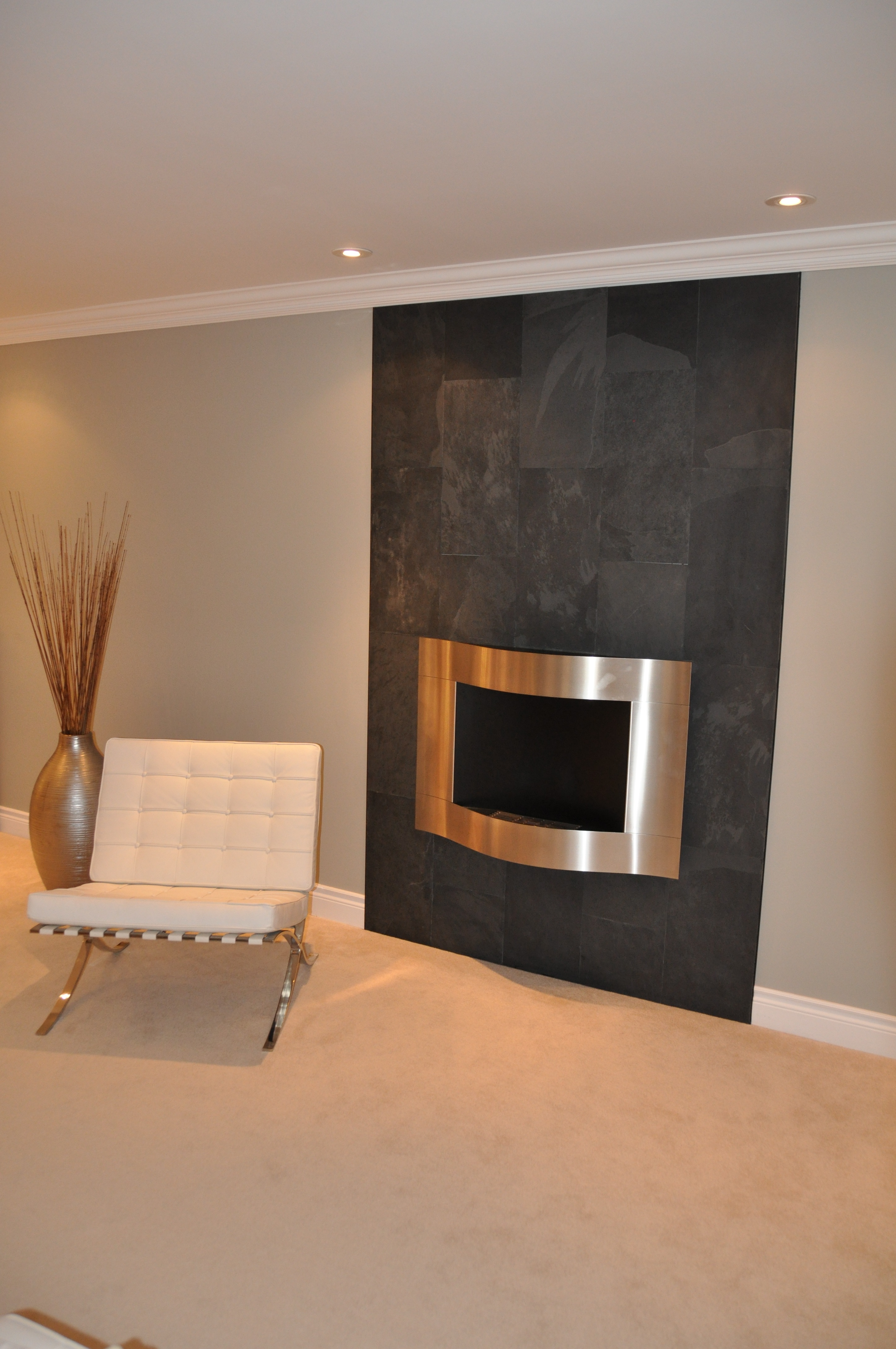 Charcoal slate feature wall with a curved steel fireplace surround in a living room