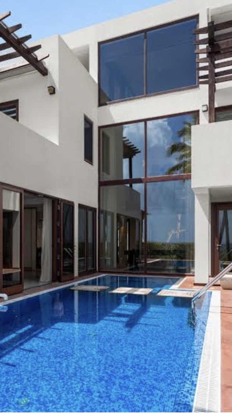 Blue glass mosaic pool beside a white stucco villa