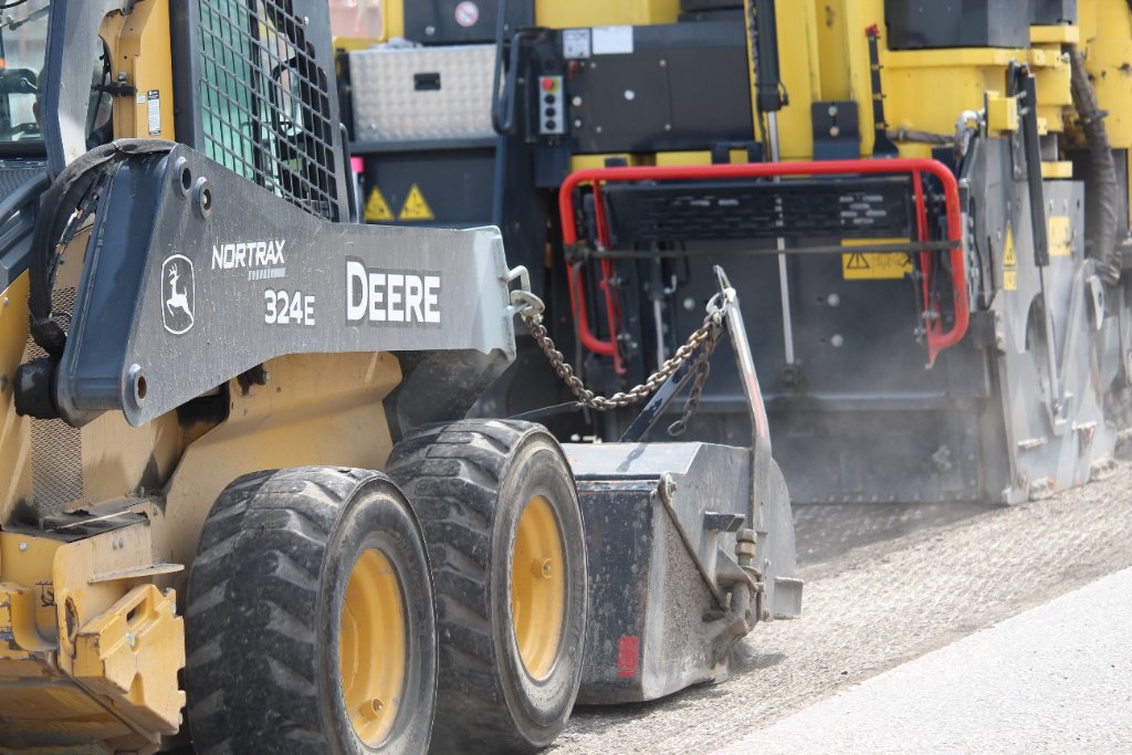 John Deere skid steer near paving equipment