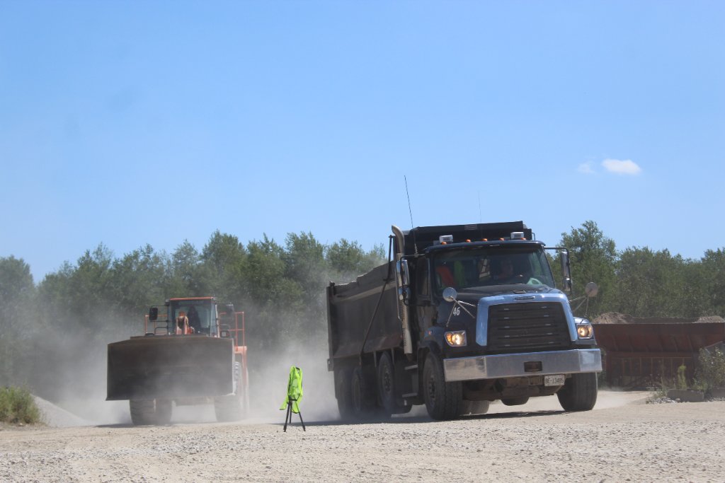 Loader and dump truck on dusty site