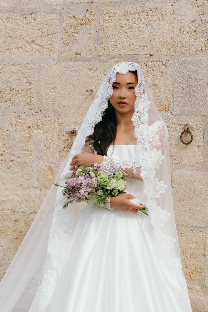 Mariée au voile devant le mur