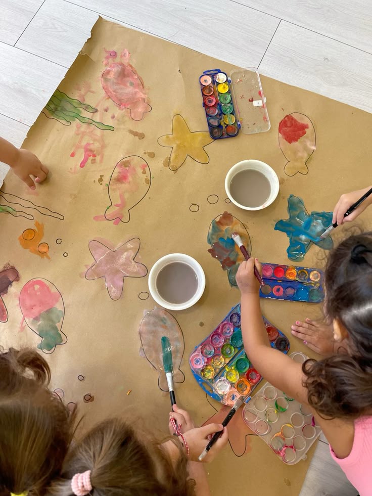 Children painting fish and starfish on craft paper