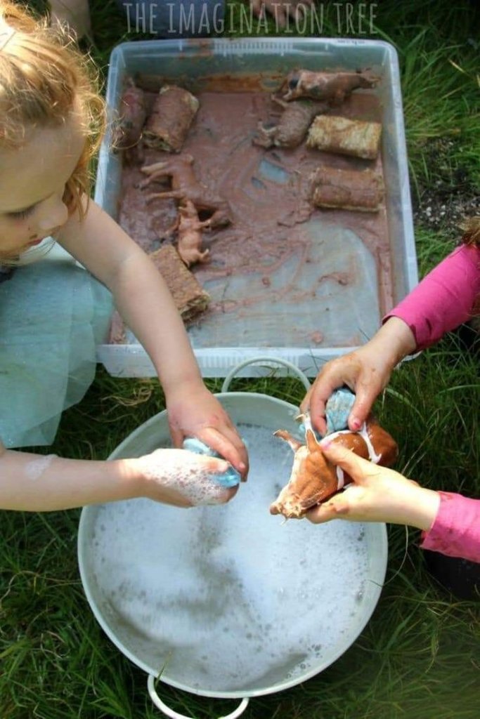 A child and adult washing muddy animal figurines