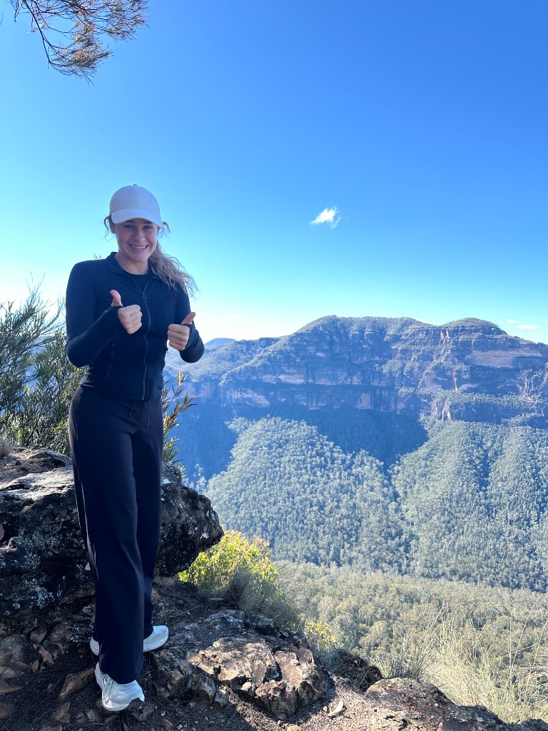 Kristin giving a thumbs up on a mountain ledge