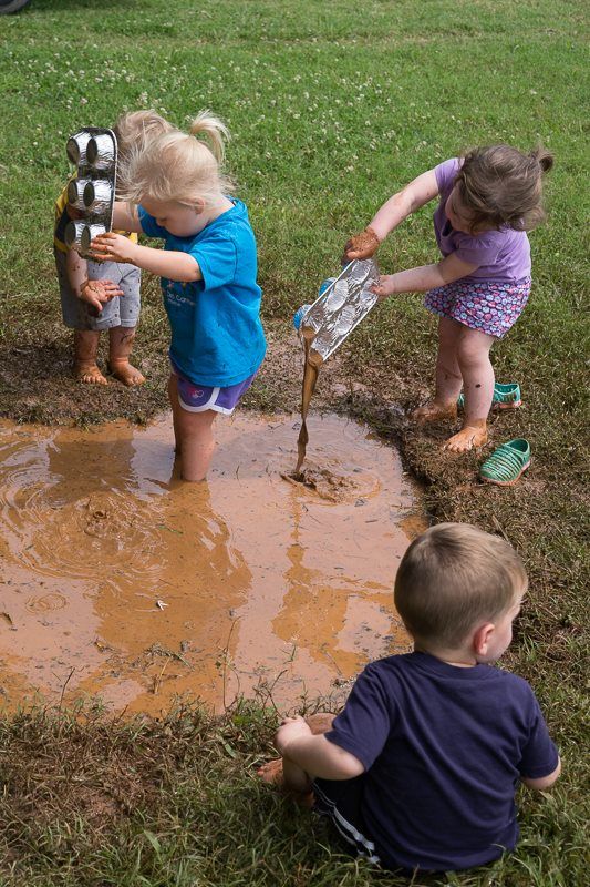 Children playing in a muddy puddle with metal muffin tins