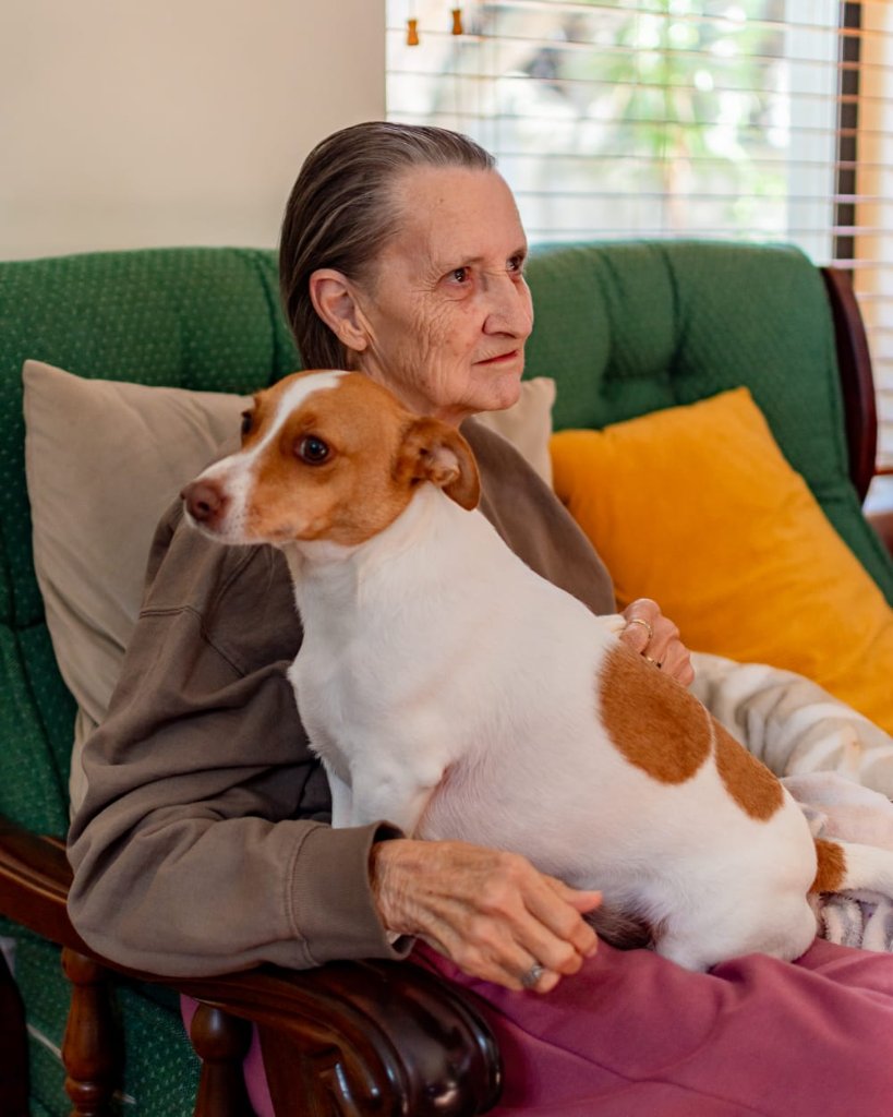 Resident cuddling a dog on a sofa