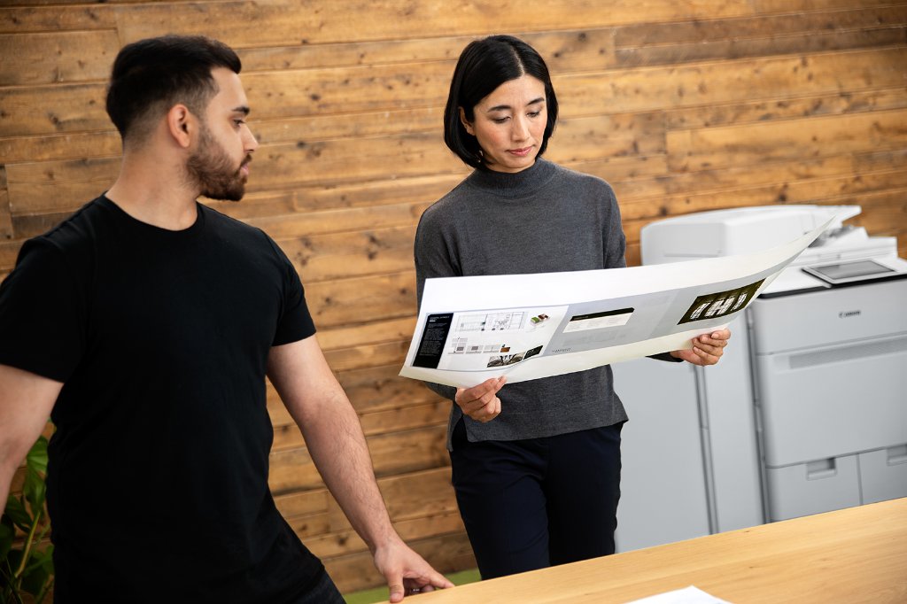 Team members collaborating in a loft office with a Canon multifunction printer