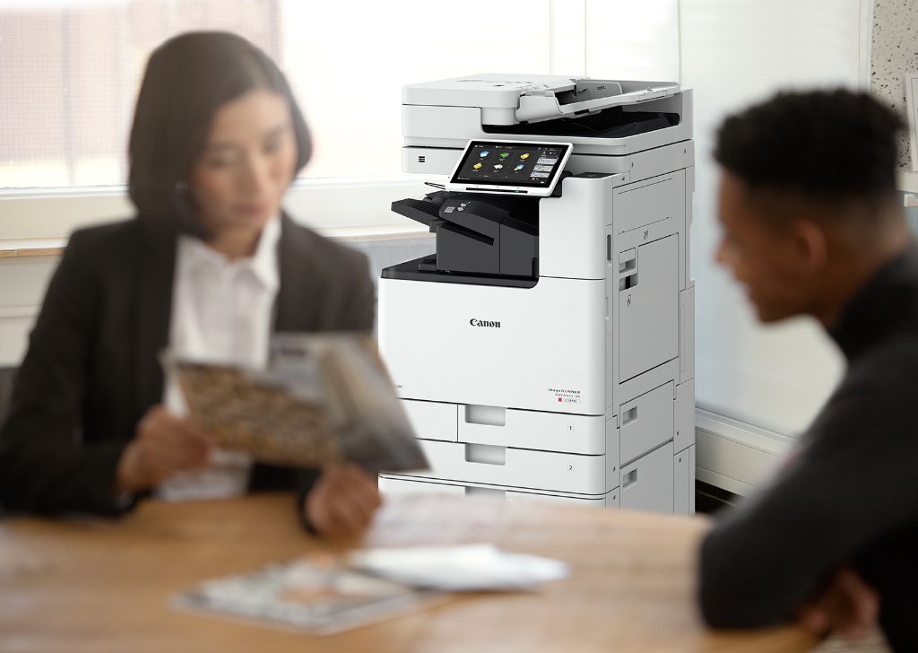 Business professionals in a meeting with a Canon imageRUNNER multifunction device in the background