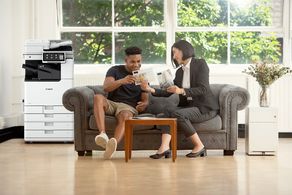 Two professionals reviewing a large document together near a Canon printer