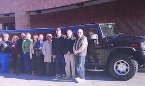Group photo beside a vehicle at a community event