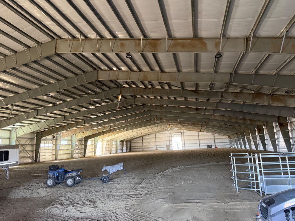 Covered steel riding arena interior with clear-span framing and groomed footing in Northern Nevada by Hoyle Construction