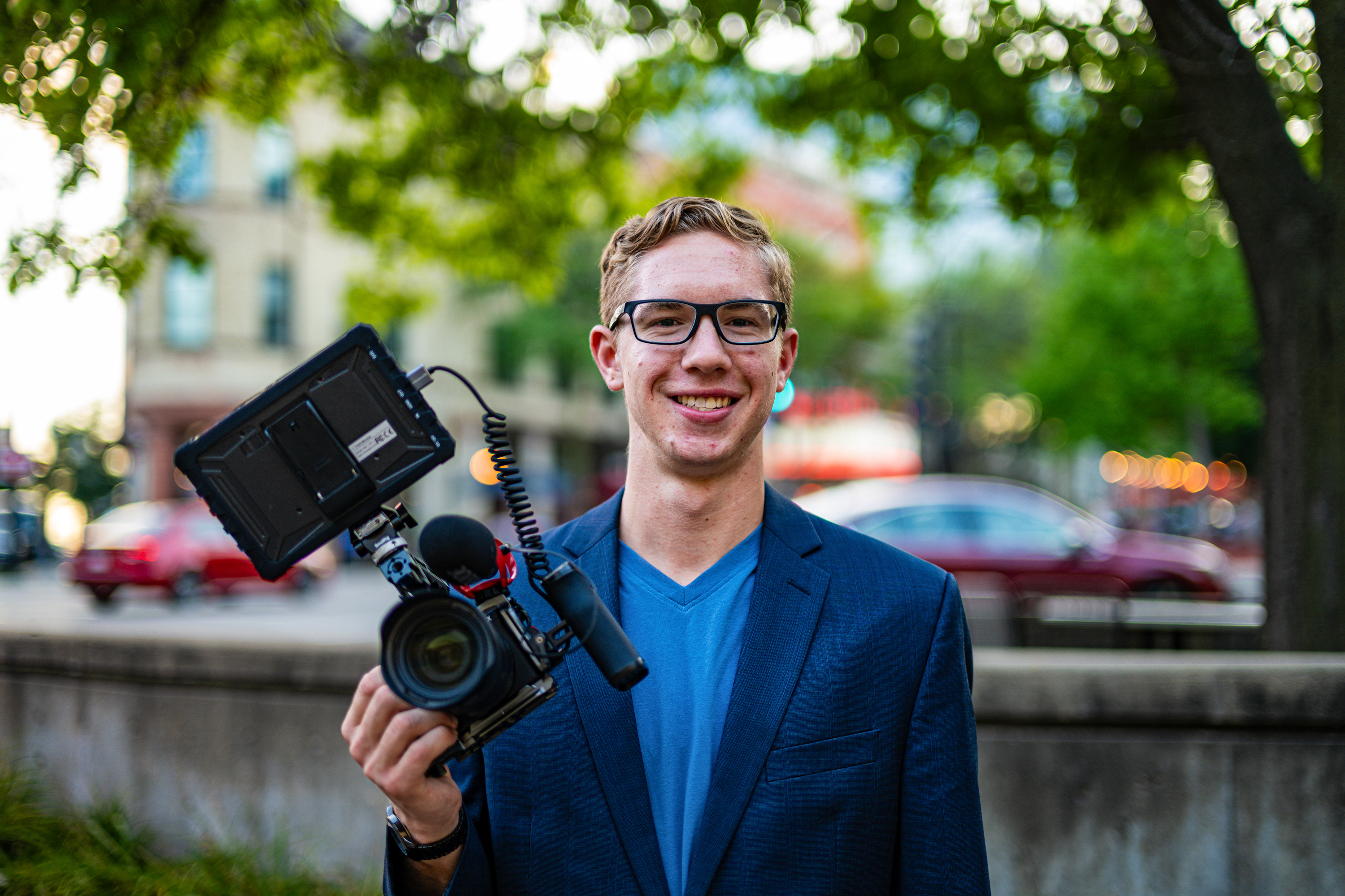 Joe Meinholz holding his camera in a navy blazer