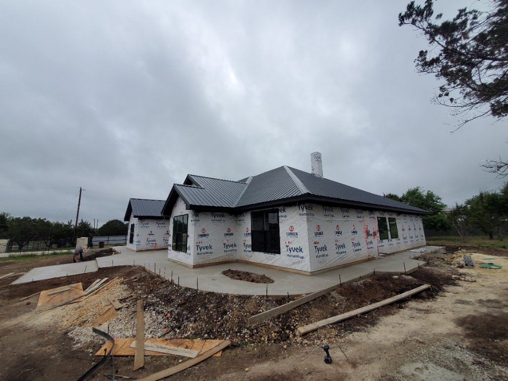 New concrete walkway wrapping around a house under construction
