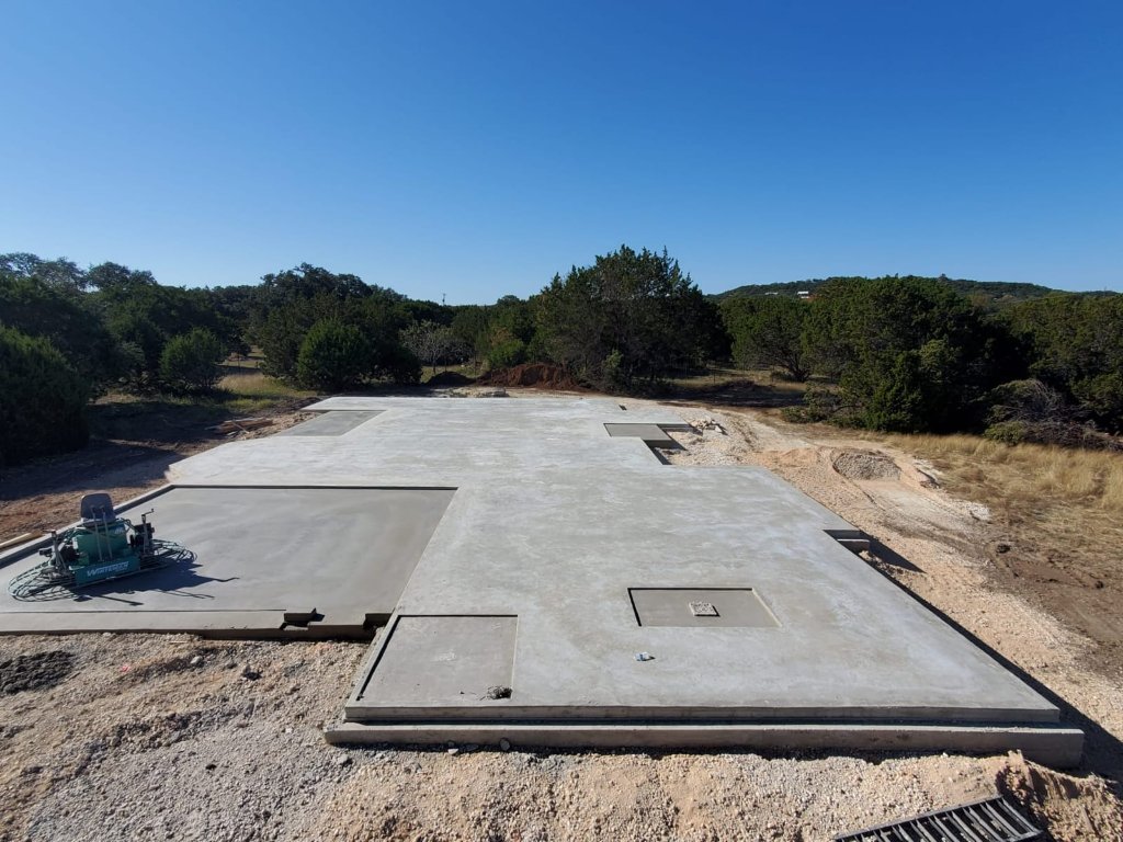Large stepped concrete foundation with power trowel on site