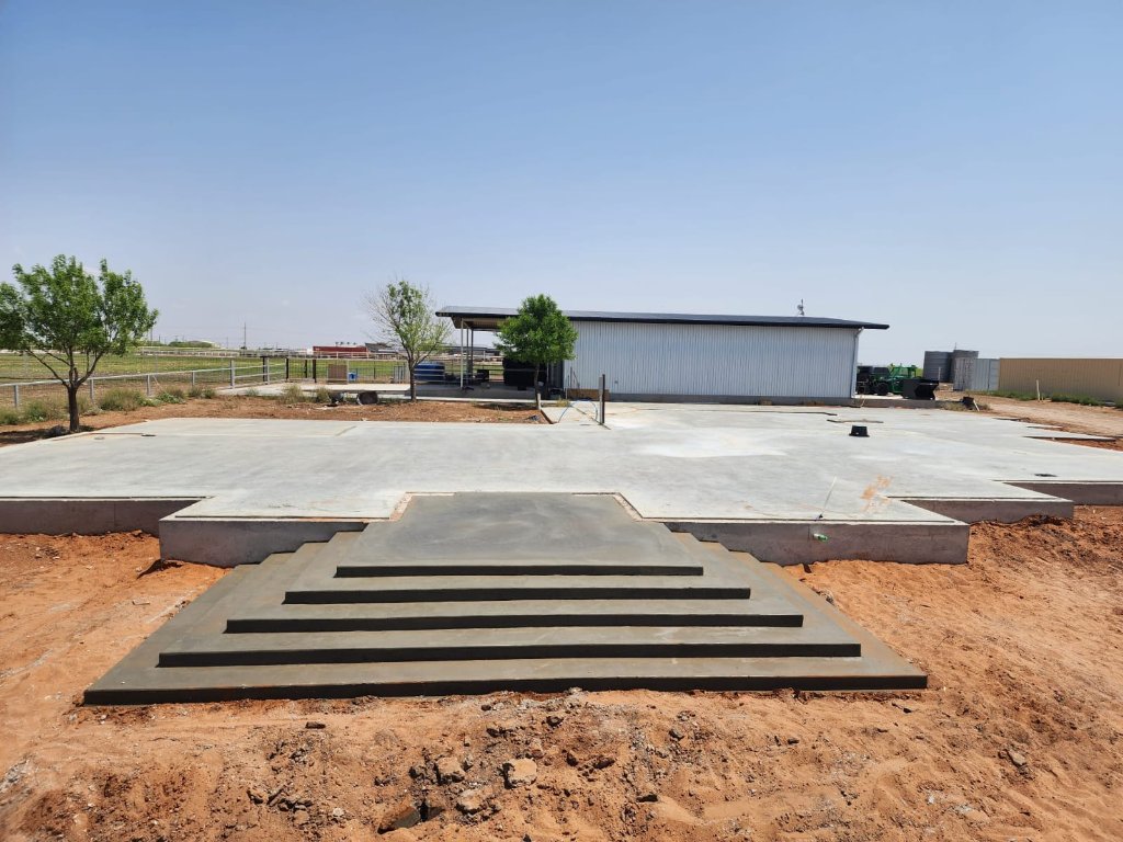PFC Construction finished concrete foundation slab with staircase leading to a metal building