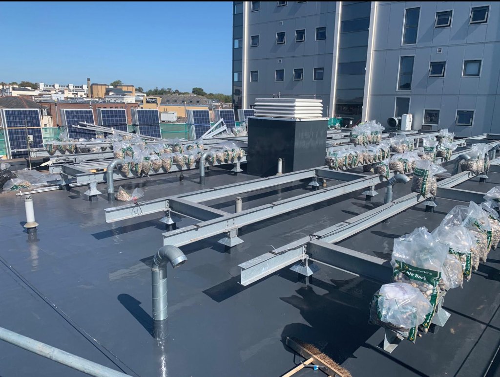 Rocathaan HotSpray large commercial roof with solar panels — polyurea roofing system
