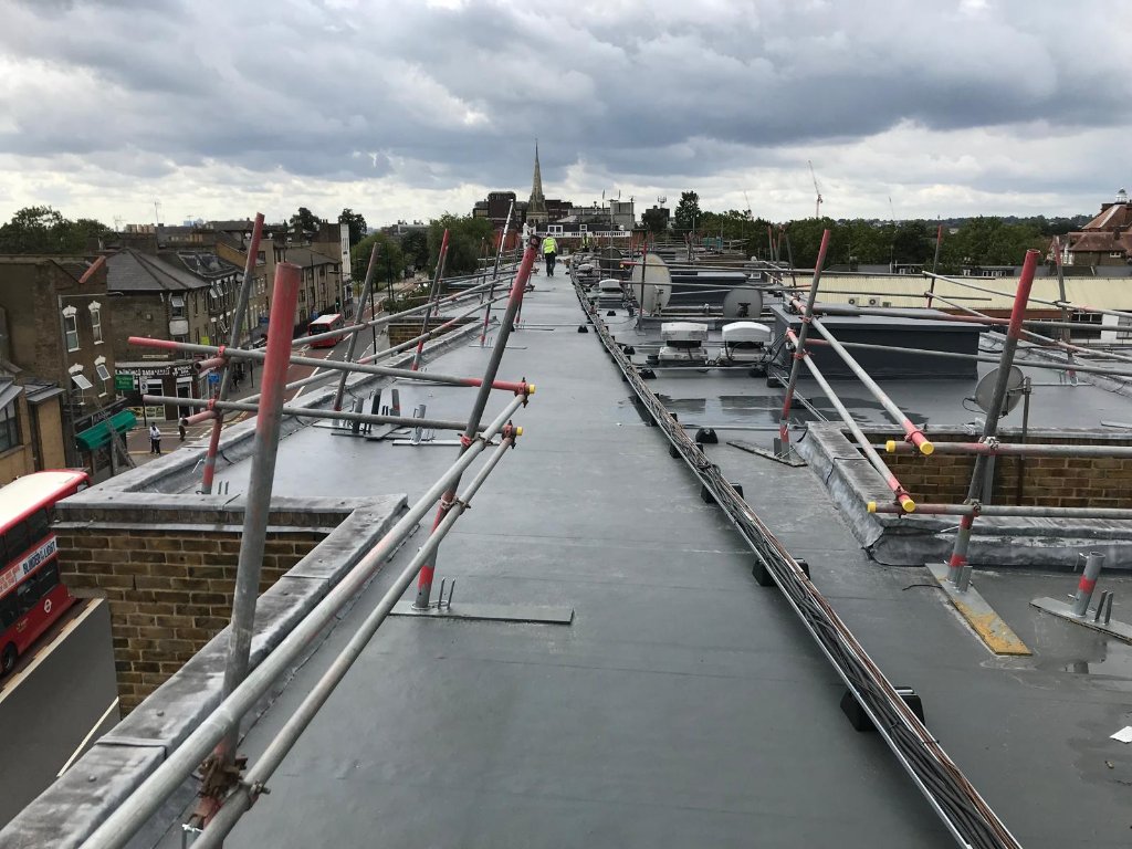 Rocathaan HotSpray large flat roof with scaffolding — industrial roof refurbishment