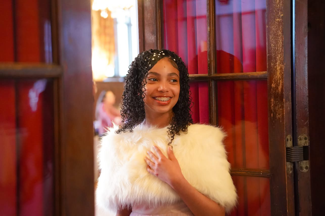 Young attendee in white fur shrug