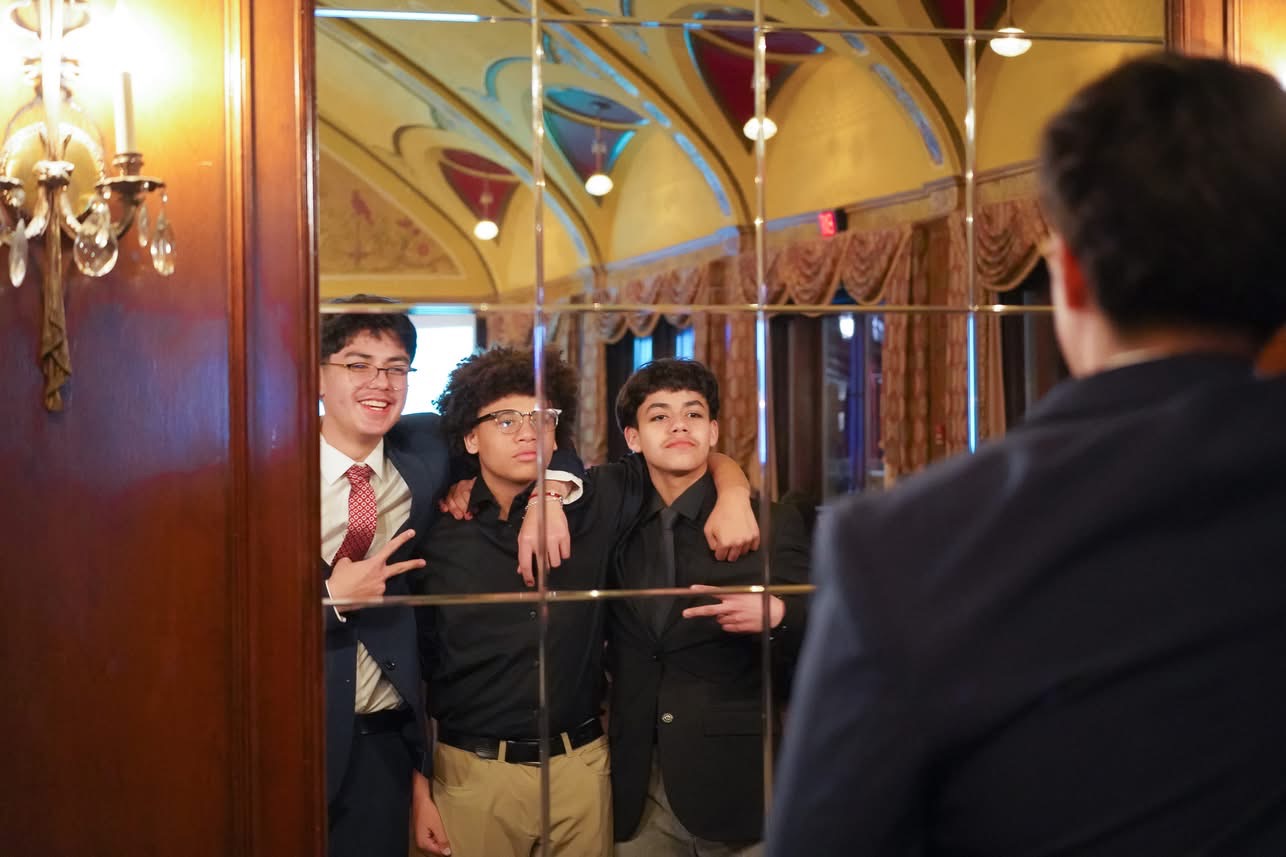 Three young men posing behind glass partition