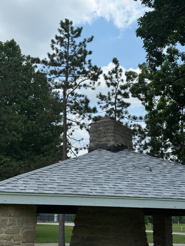 Completed ridge cap repair near stone chimney