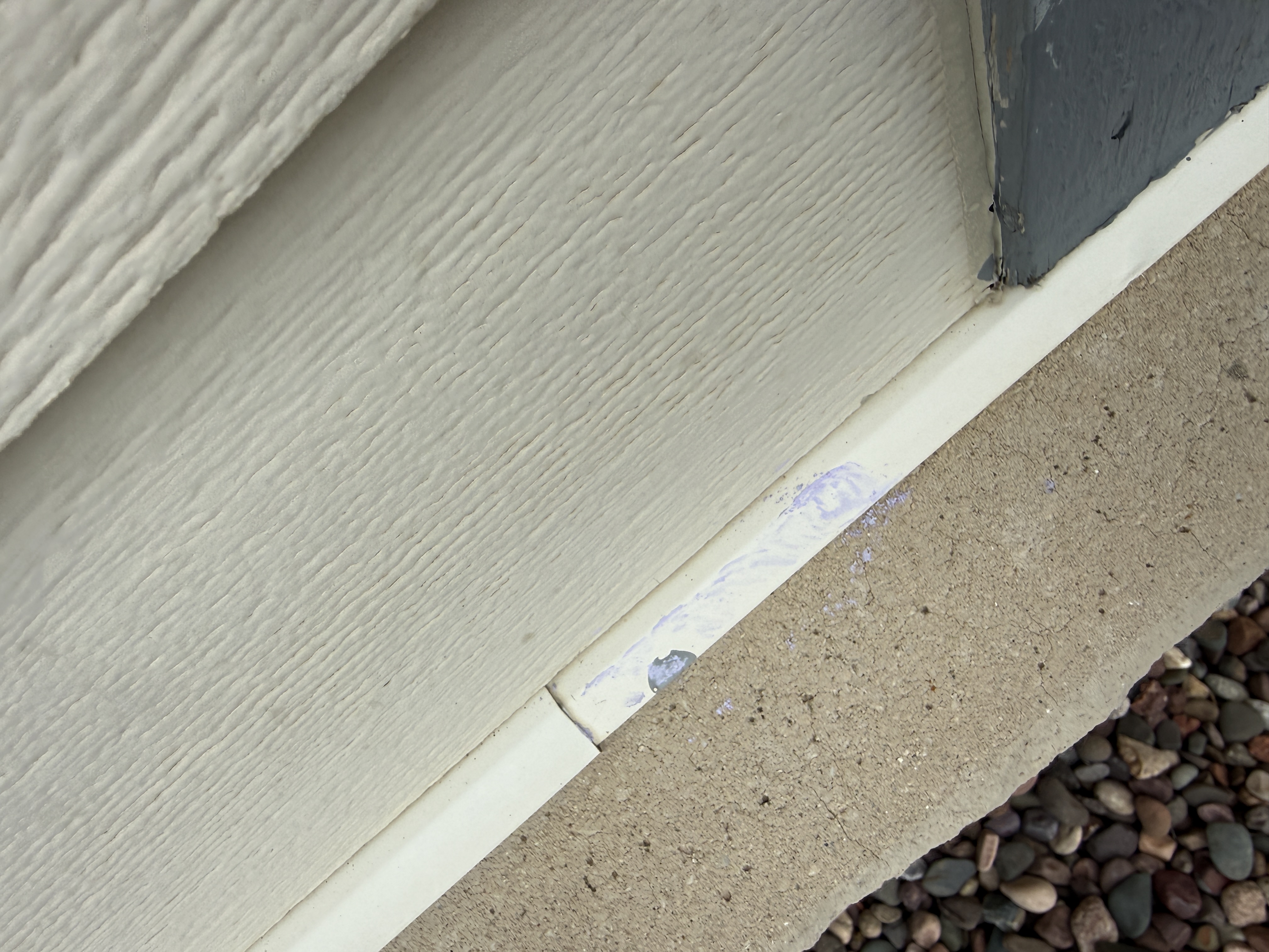 Exterior siding trim scuffing and residue at the foundation