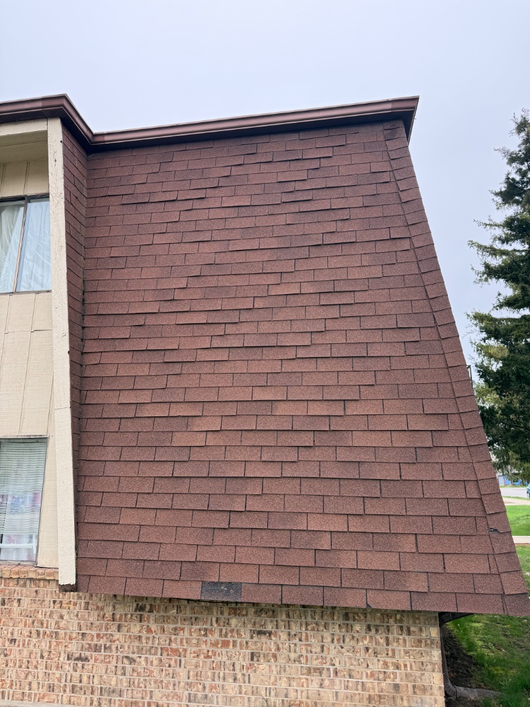 Storm-damaged roof — wavy shingle courses and missing shingle exposing underlayment