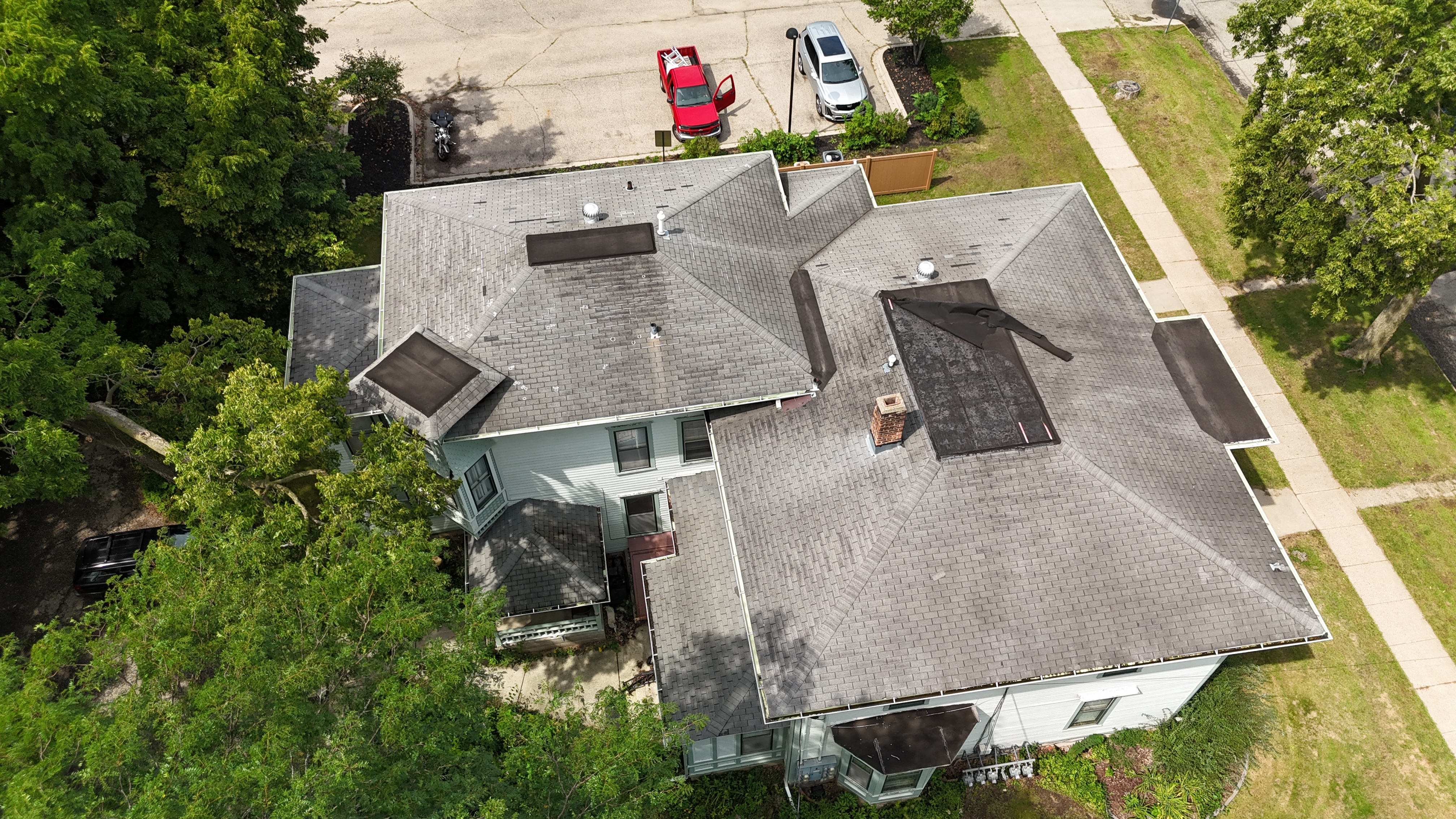 Aerial drone view of residential roof with a dark damaged patch on the right slope