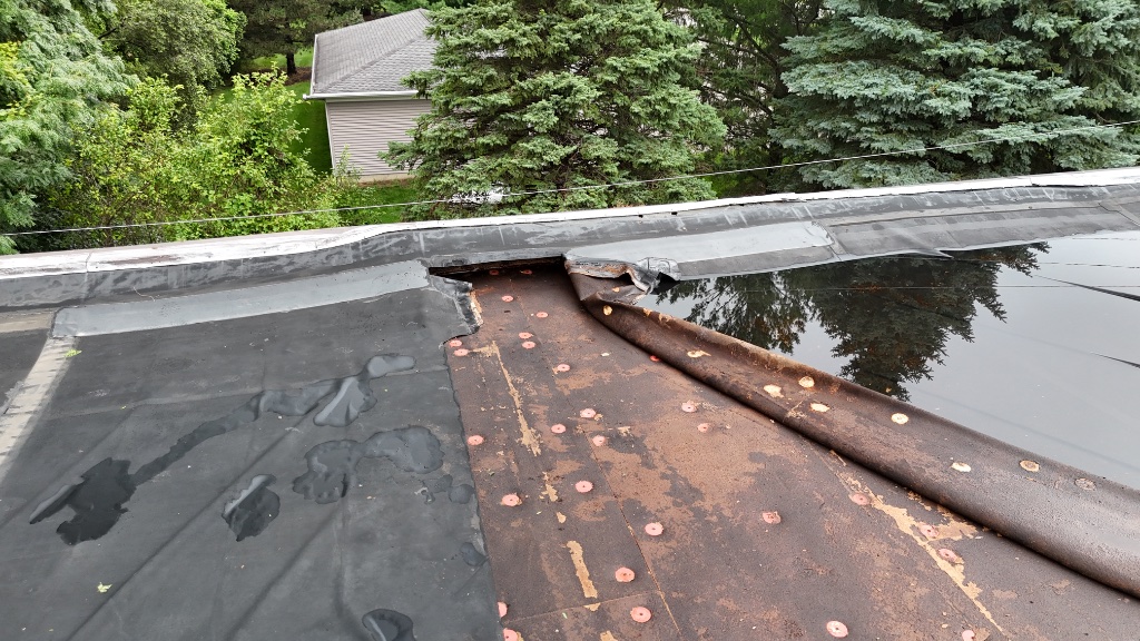 Storm-damaged flat roof — EPDM membrane ripped from base