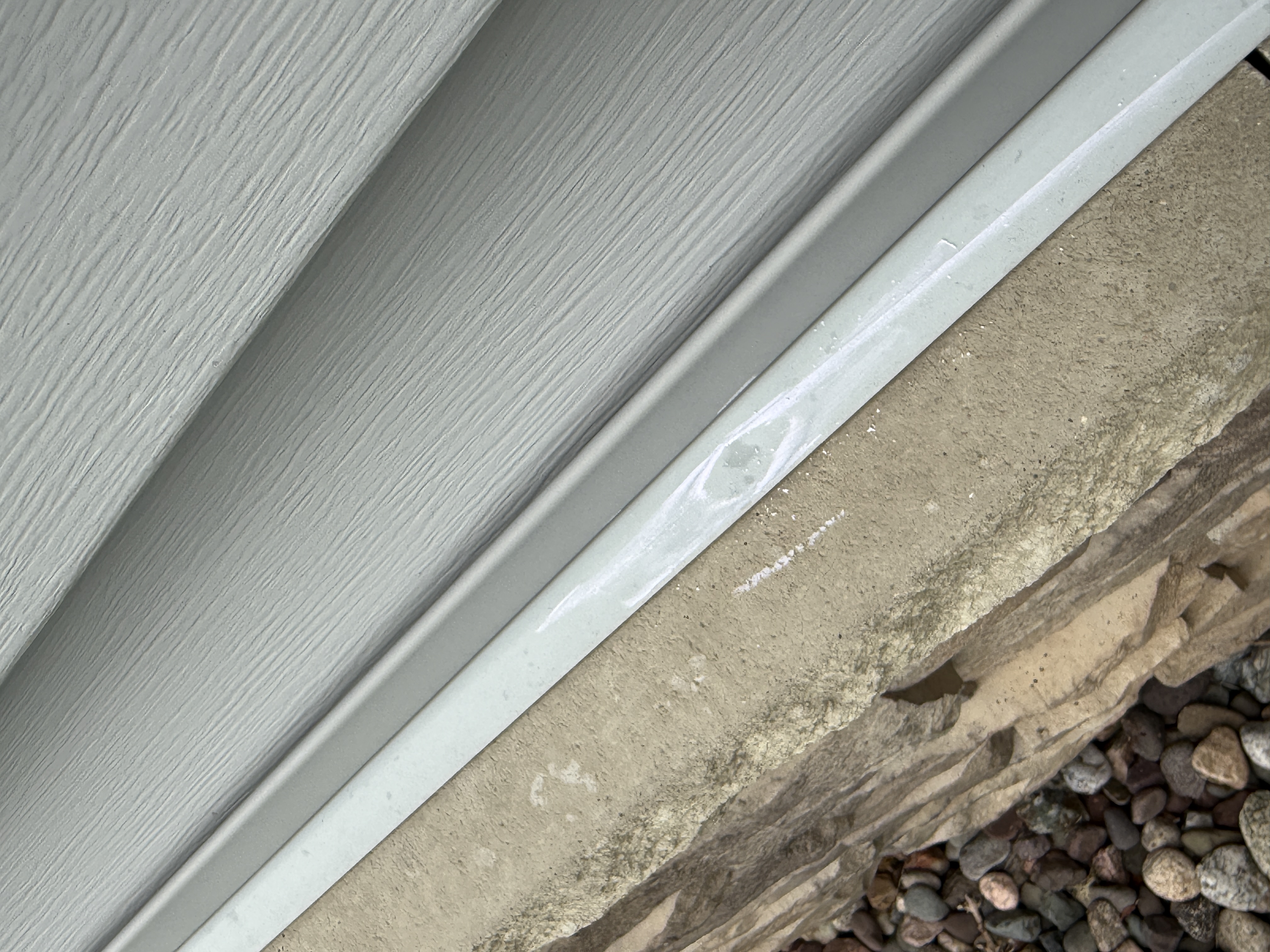 Vinyl siding, white trim, and concrete foundation with wear