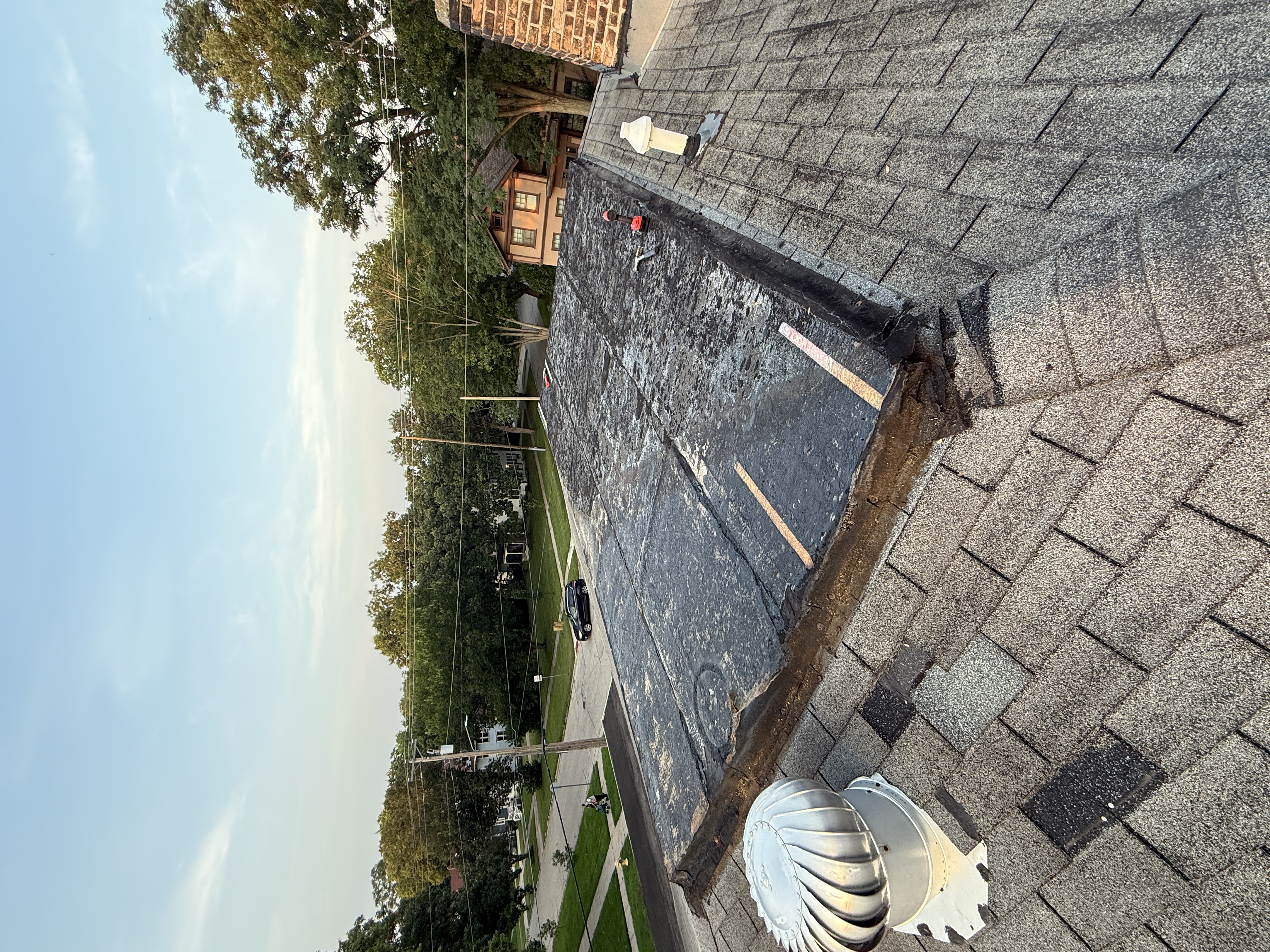 Old EPDM rubber roofing membrane peeled back from the roof deck after wind damage